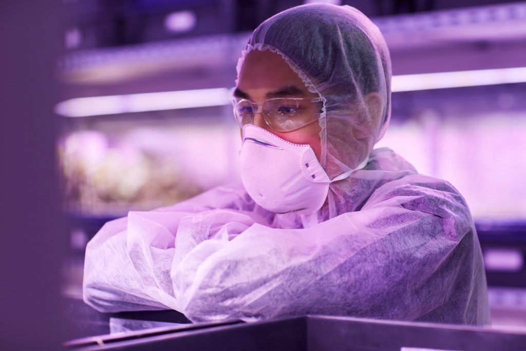 Asian scientist in protective clothing and protective mask working with chemicals